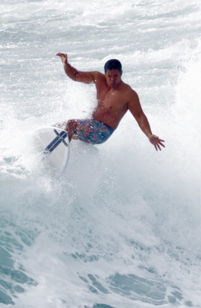 A surfer maneuvers skillfully on a wave, displaying dynamic balance and control. The image captures the excitement of surfing.