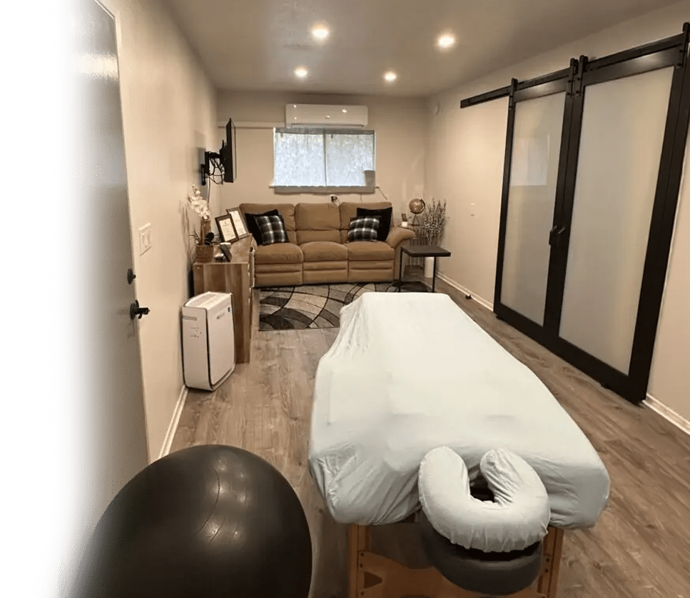 Serene therapy room featuring a massage table, couch, and exercise ball, designed for relaxation and wellness sessions.